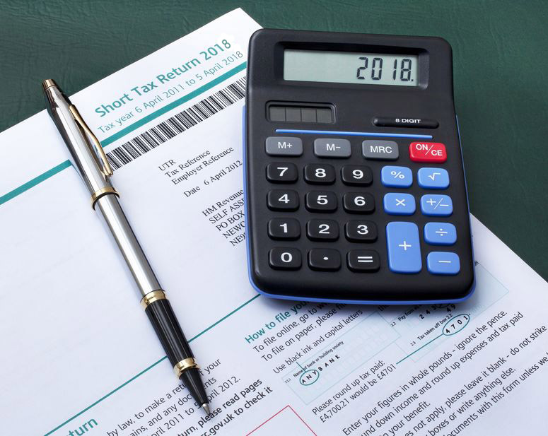 14692595 - british tax return form with calculator and pen
