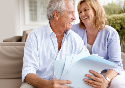 elderly couple laughing with paperwork