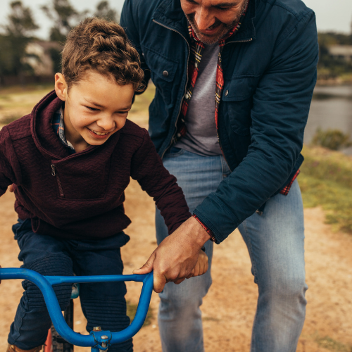 father helping son ride bike